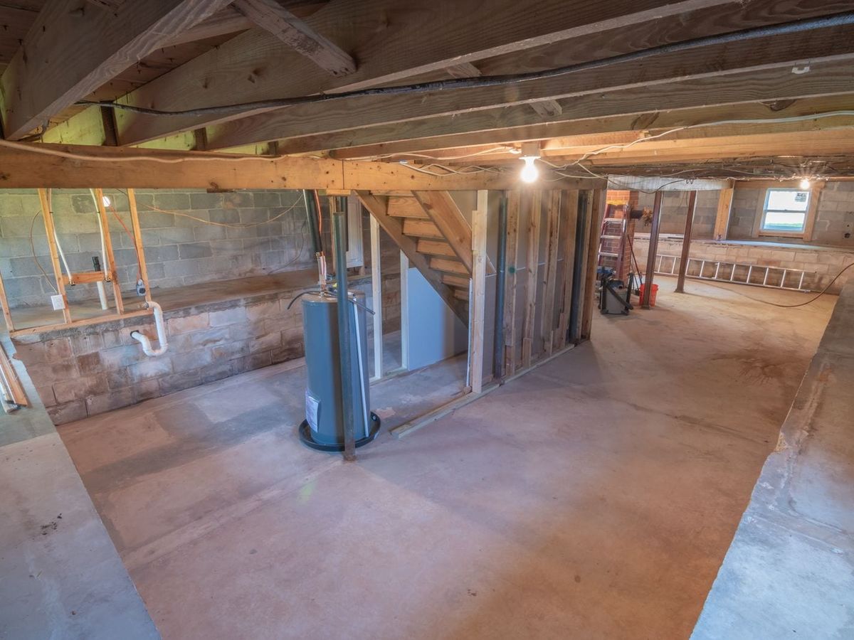 Unfinished basement with poured concrete slab floor and exposed plumbing
